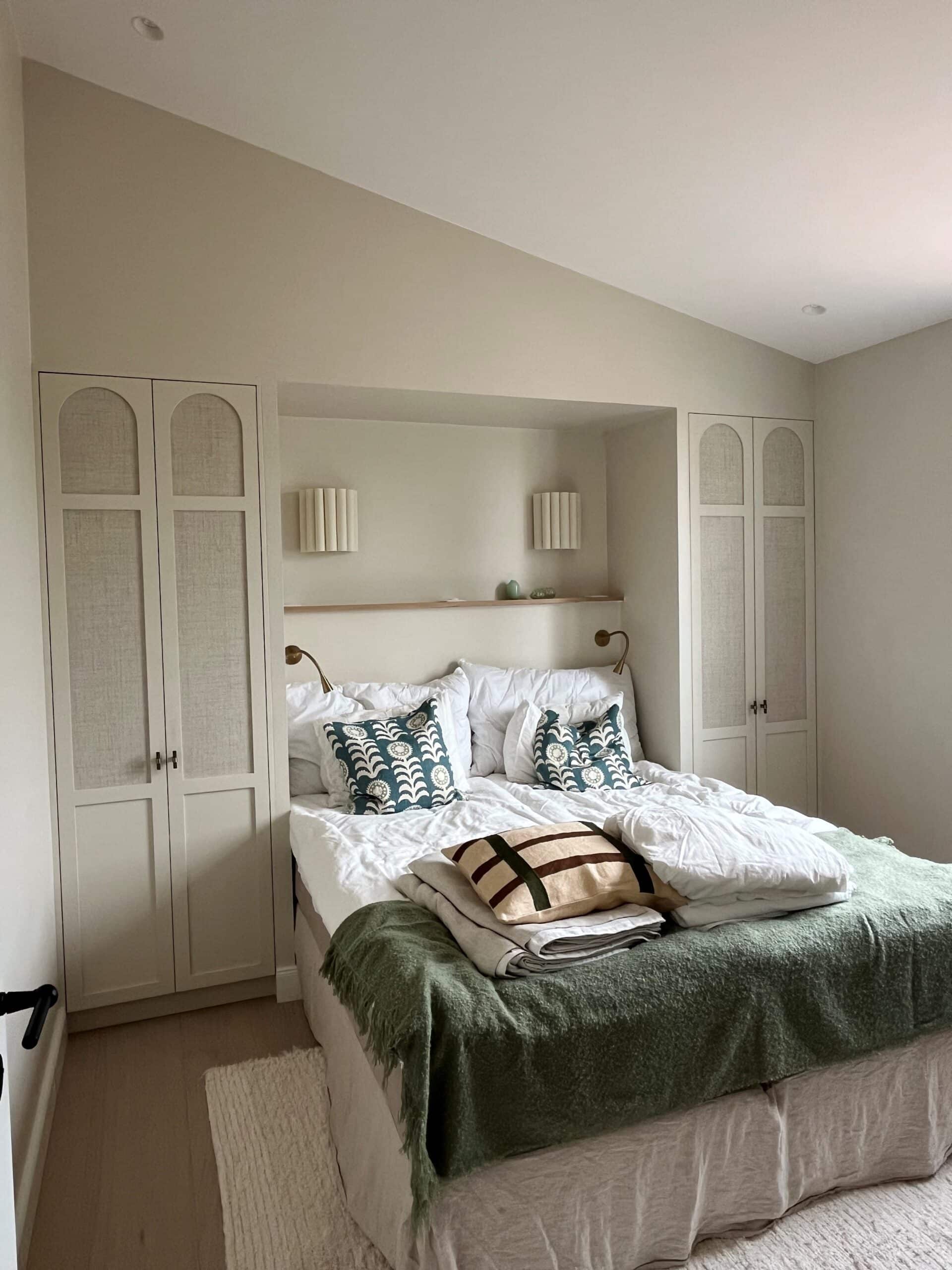 Chambre cosy avec lit encastré entre deux armoires à arches, jeté de lit vert et coussins décoratifs.
