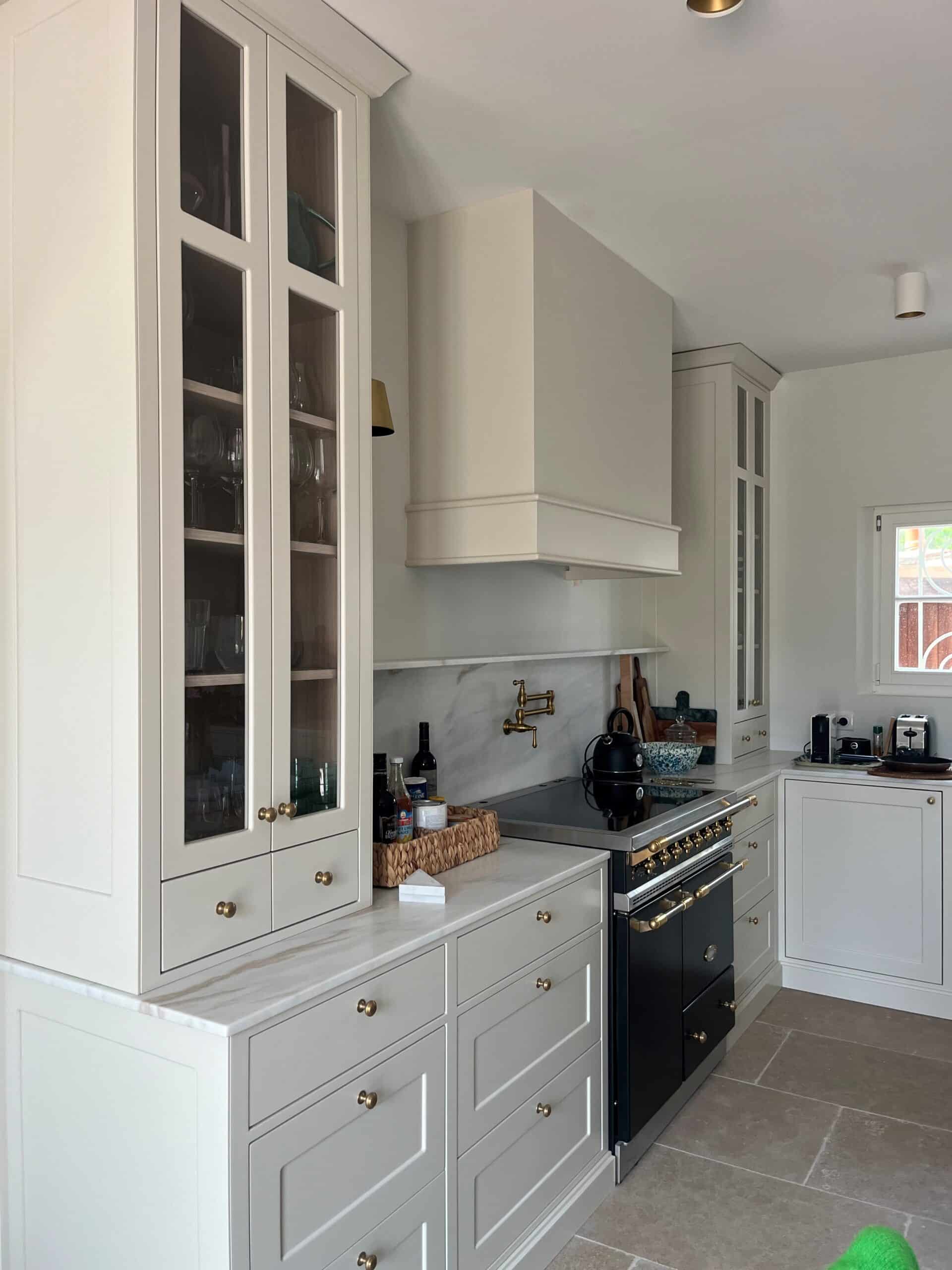 Cuisine élégante avec armoires crème, piano de cuisson noir, comptoirs en marbre et détails en laiton raffinés.