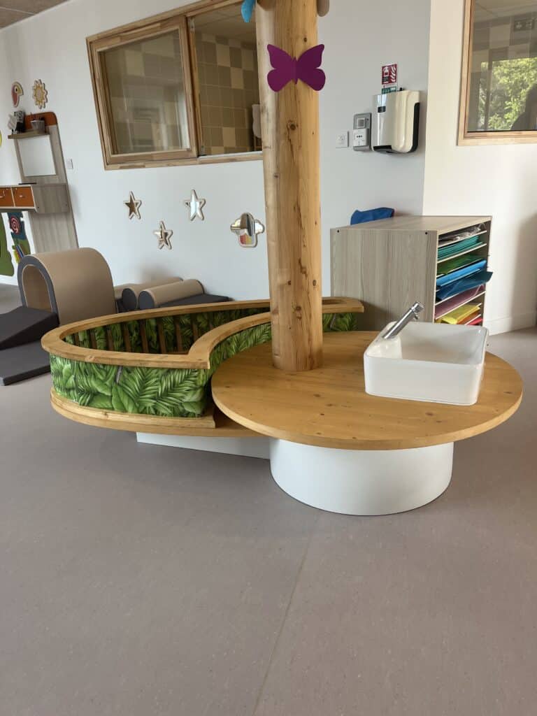Mobilier de crèche en bois avec évier intégré et espace de jeu thématique jungle pour l'éveil des enfants.
