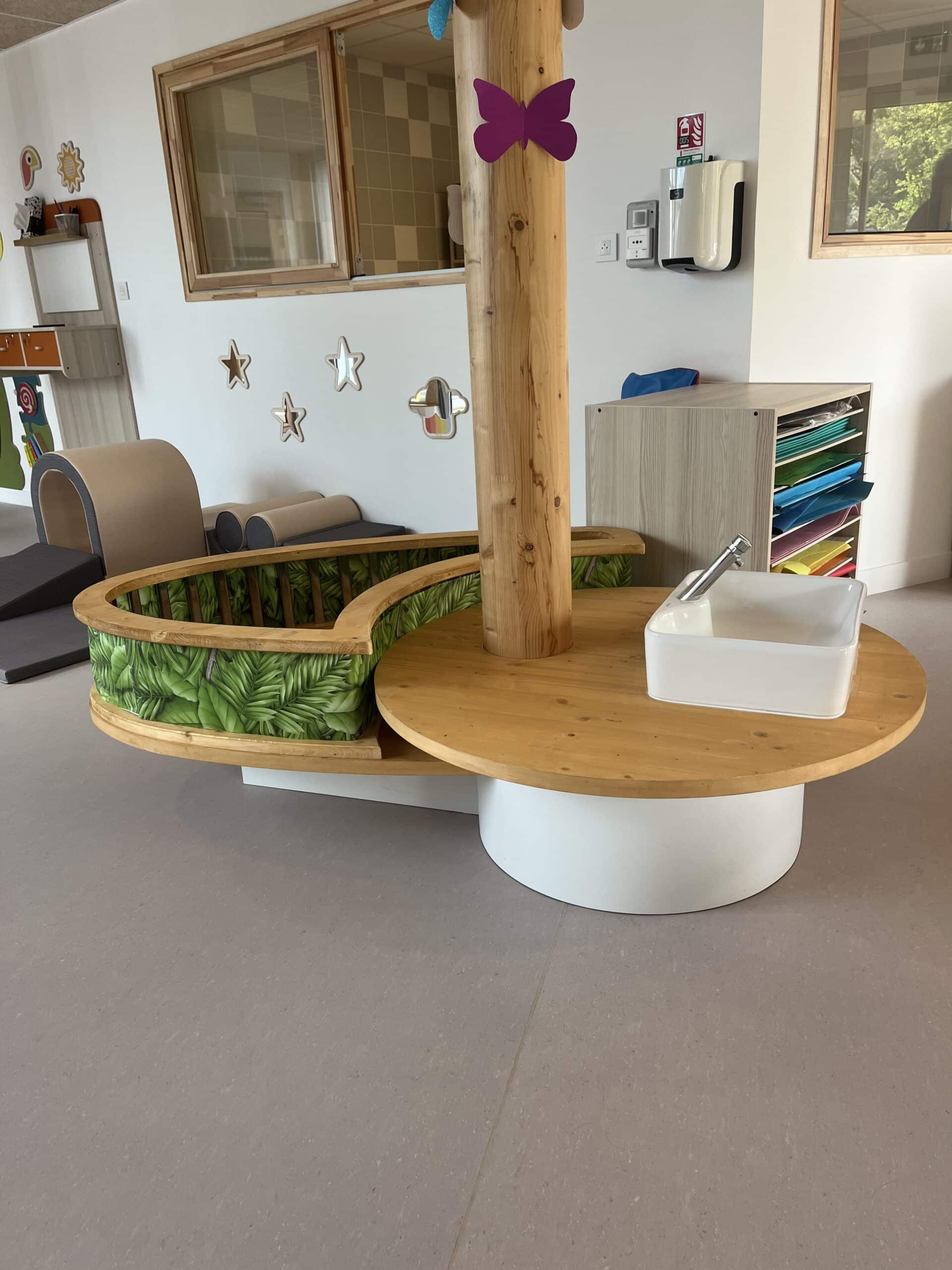 Mobilier de crèche en bois avec évier intégré et espace de jeu thématique jungle pour l'éveil des enfants.