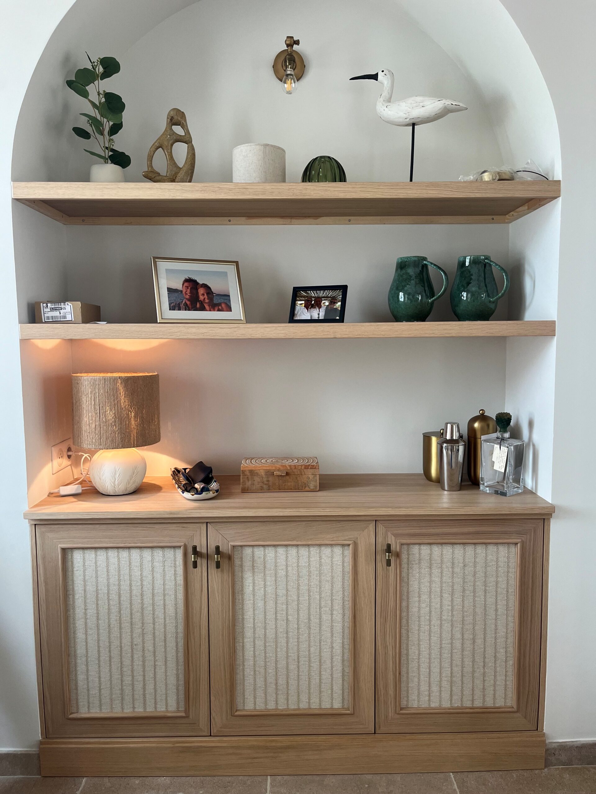 Niche cintrée avec étagères en bois, buffet aux portes en tissu et décoration élégante de style bohème.