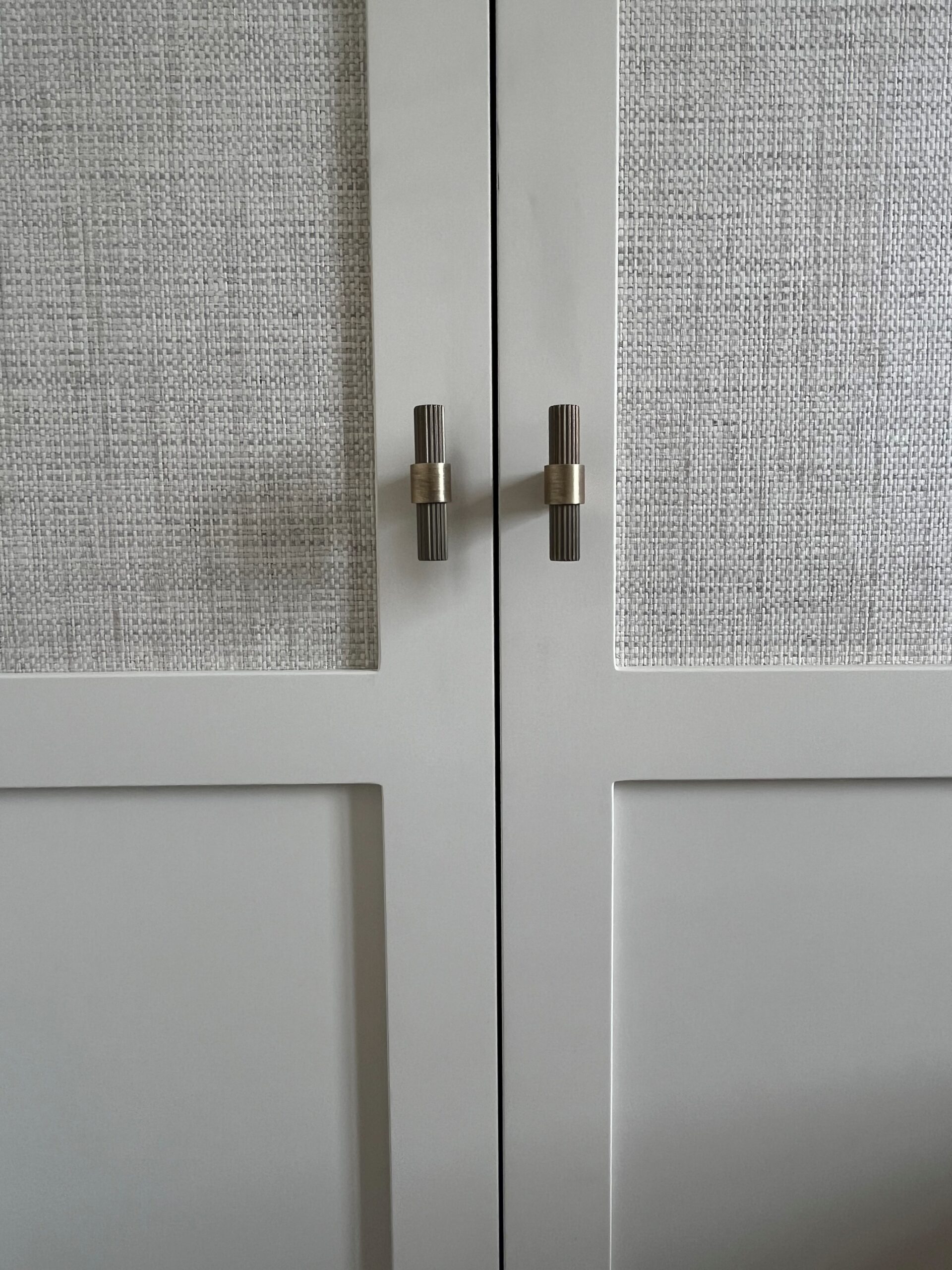 Portes de placard en raphia tressé avec poignées en laiton cannelé élégantes.