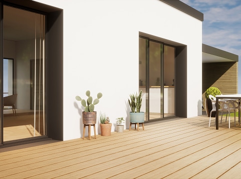 Terrasse moderne en bois clair avec plantes grasses et cactus devant une façade blanche, accès par de grandes baies vitrées coulissantes.
