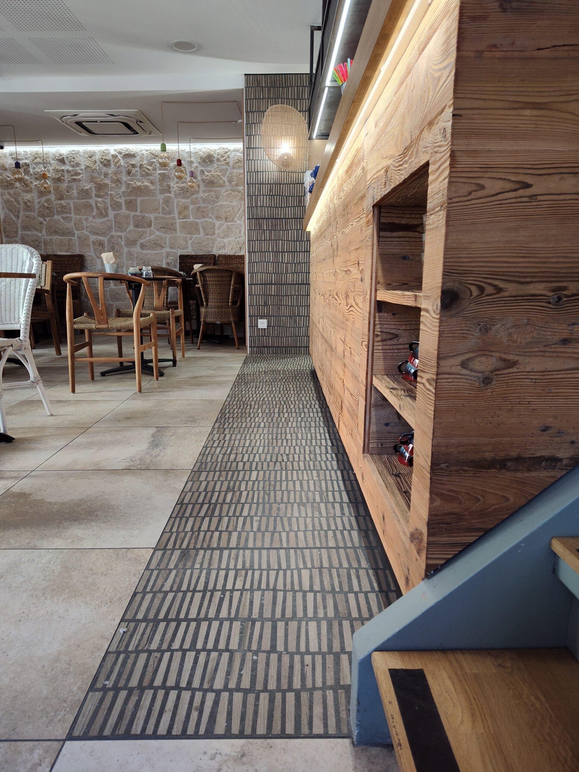 Intérieur chaleureux de restaurant avec comptoir en bois massif, mur en pierre et chaises rustiques design.